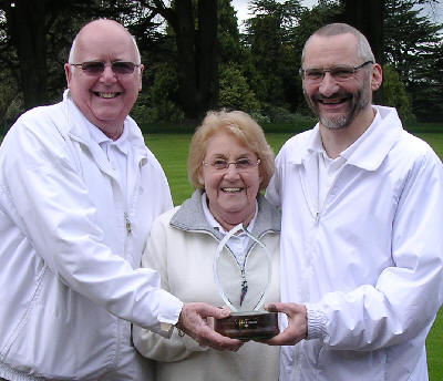 Captain Rod Payne (left) presents the trophy to Kath Matthews and Quentin Smith