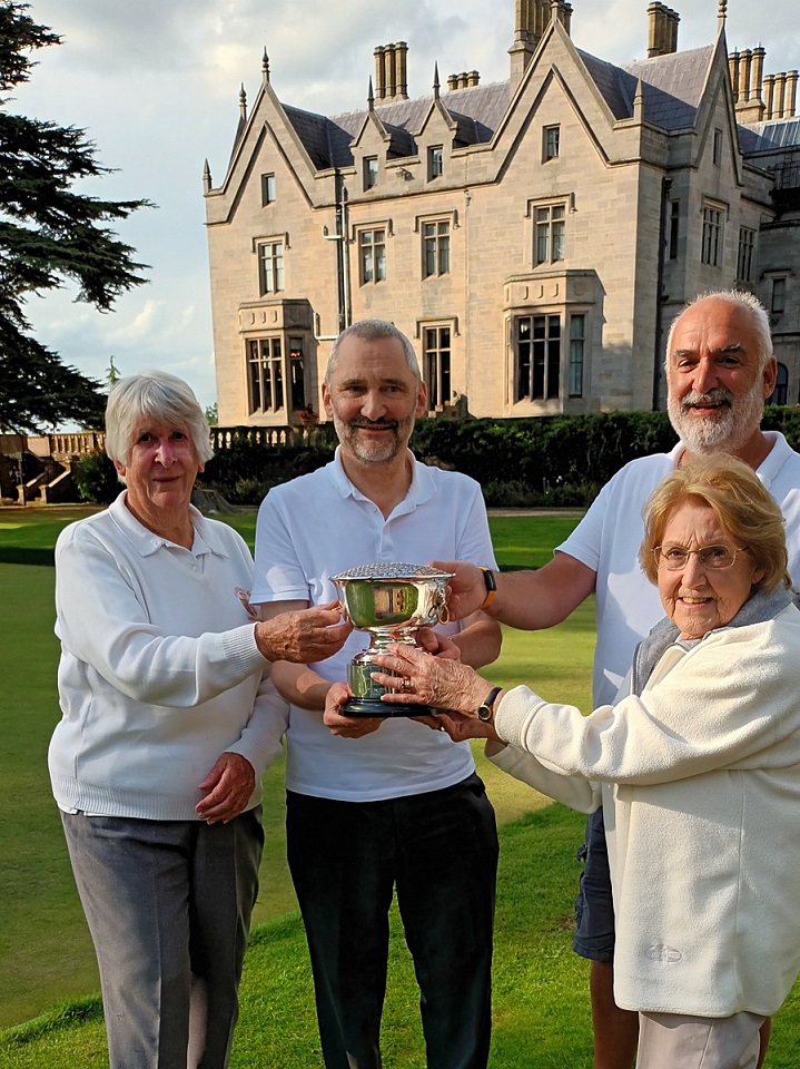 lady presents silver trophy to three bowlers